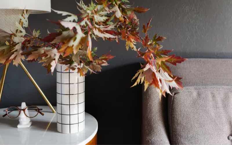 A burgandy wall with a fall floral arrangement.