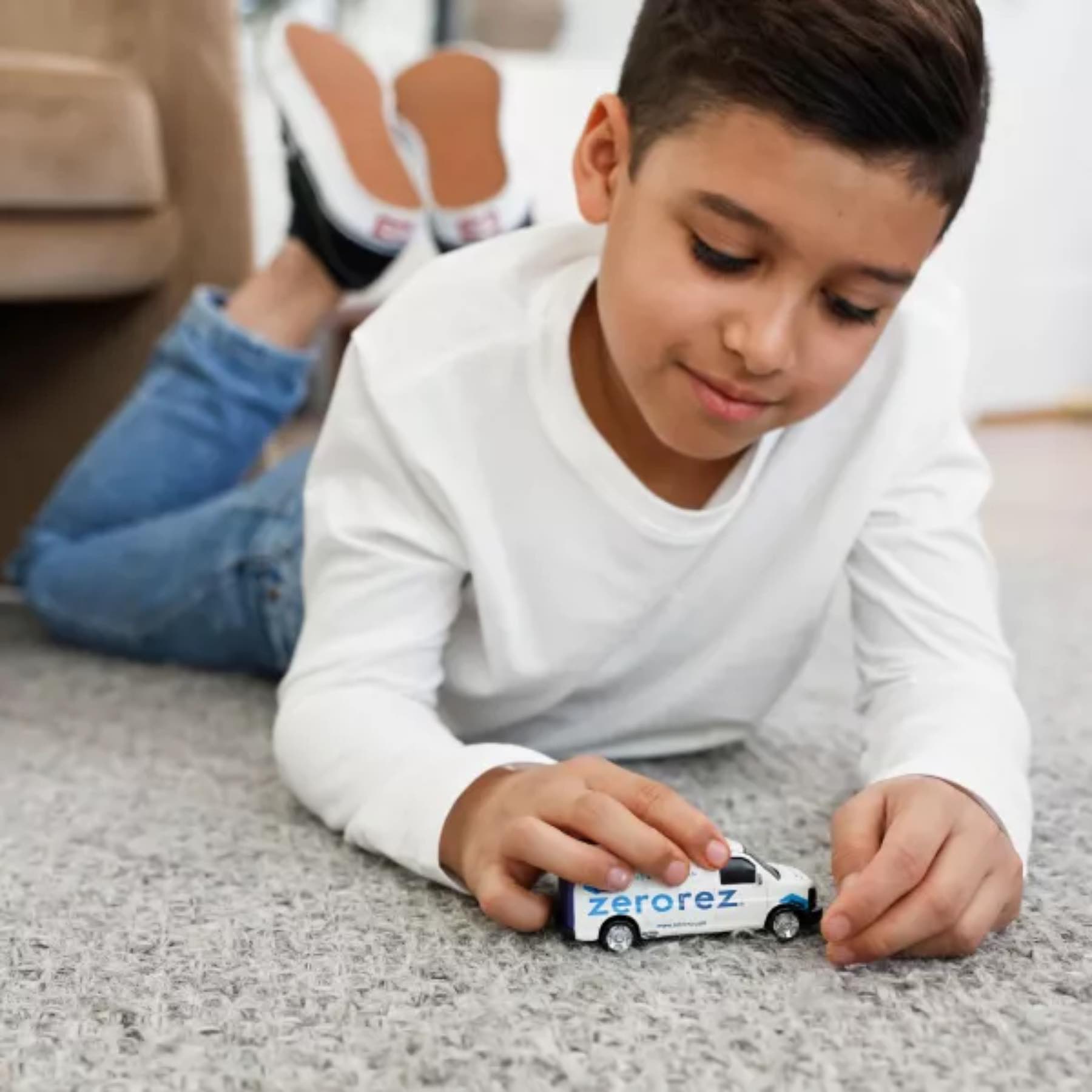 A child playing with a toy Zerorez van on soft carpet.